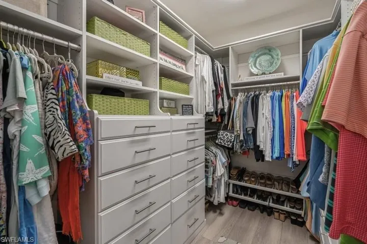 Walk in closet with light hardwood / wood-style floors