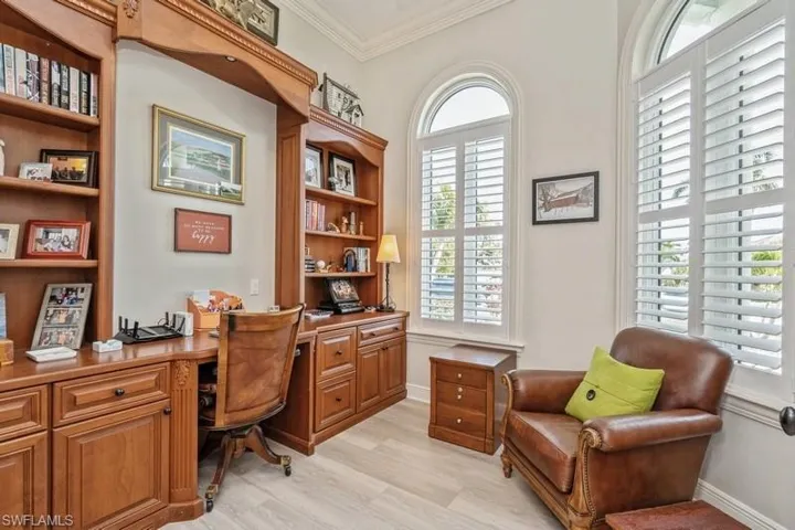 Home office featuring crown molding, built in desk, and light hardwood / wood-style floors