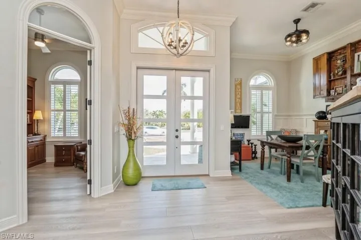 Doorway to outside featuring ornamental molding, a chandelier, light hardwood / wood-style floors, and french doors