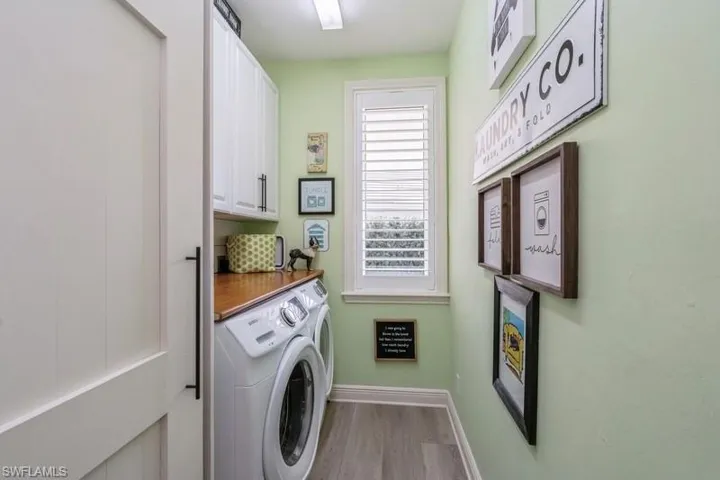 Laundry room with cabinets, washer and clothes dryer, and light hardwood / wood-style flooring