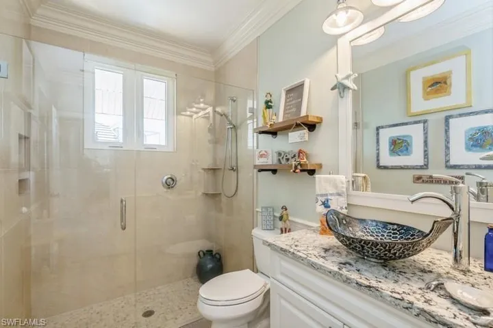 Bathroom with vanity, crown molding, a shower with shower door, and toilet