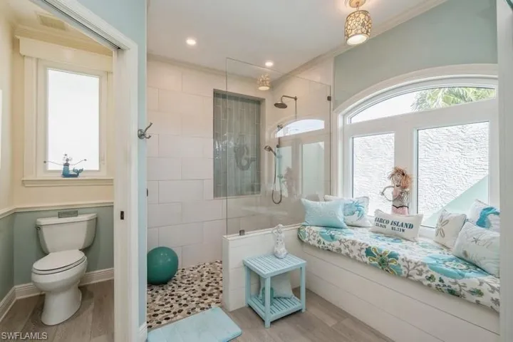 Bathroom featuring tiled shower, ornamental molding, toilet, and hardwood / wood-style floors