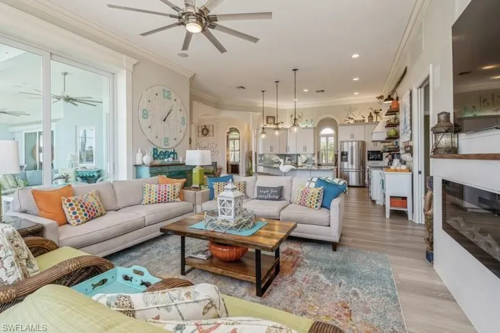 Living room featuring ceiling fan, ornamental molding, and light hardwood / wood-style flooring