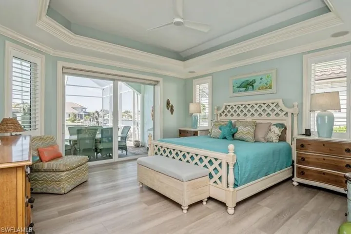 Bedroom with light hardwood / wood-style floors, access to outside, ceiling fan, and a tray ceiling