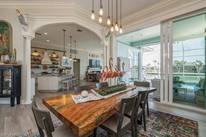 Dining space with hardwood / wood-style flooring, ornamental molding, and decorative columns