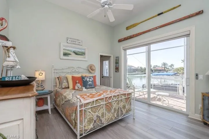 Bedroom with a water view, access to exterior, ceiling fan, and light hardwood / wood-style flooring