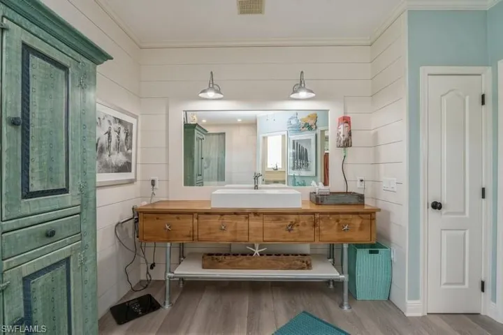 Bathroom with hardwood / wood-style flooring, vanity, crown molding, and wood walls