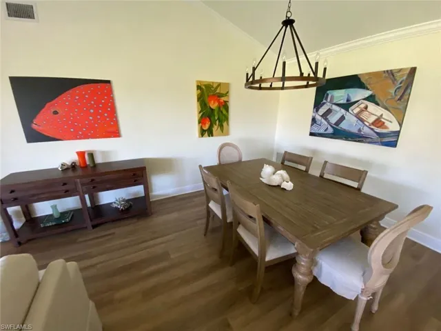 Dining room featuring dark wood-style floors, ornamental molding, and a chandelier