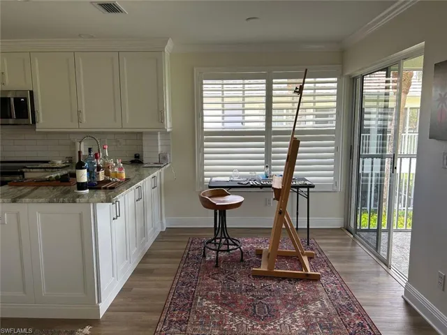 Kitchen featuring healthy amount of natural light, white cabinets, dark stone countertops, and crown molding