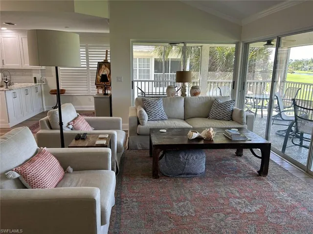 Living room featuring plenty of natural light, dark wood-style flooring, vaulted ceiling, and ornamental molding