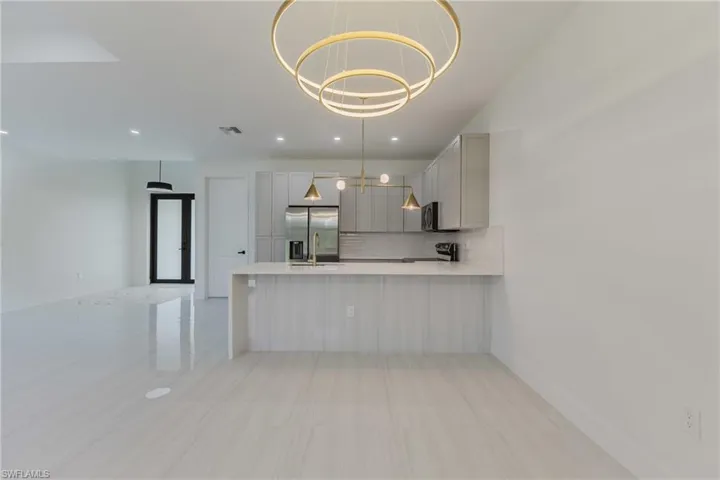 Kitchen with decorative backsplash, decorative light fixtures, gray cabinets, a peninsula, and stainless steel appliances