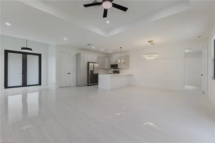 Unfurnished living room with recessed lighting, a raised ceiling, a ceiling fan, and light tile patterned floors