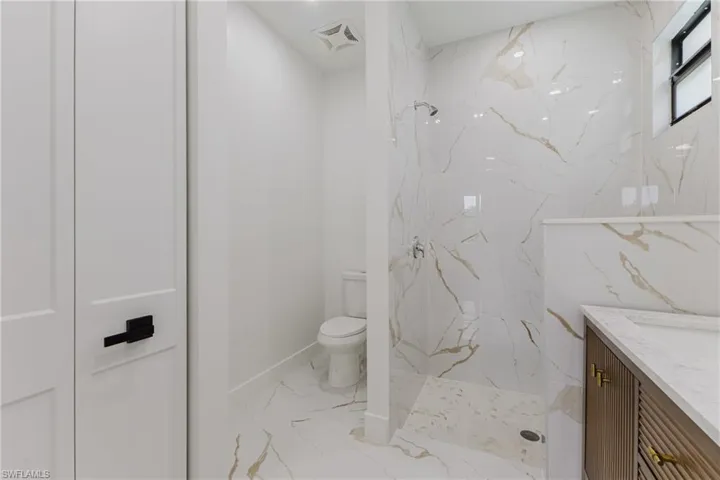 Full bathroom featuring a marble finish shower, vanity, and light marble finish floors