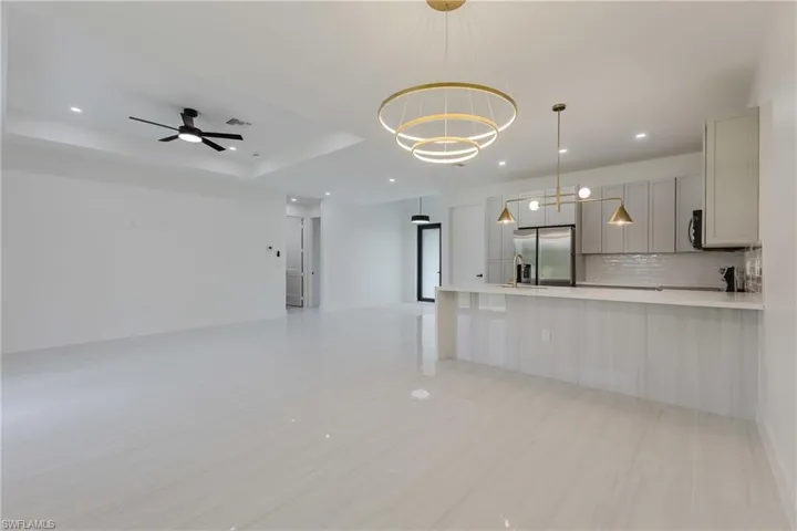 Kitchen featuring open floor plan, recessed lighting, stainless steel fridge, backsplash, and hanging light fixtures