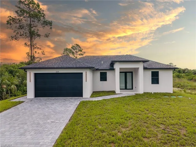 Prairie-style home with stucco siding, decorative driveway, a shingled roof, and a garage