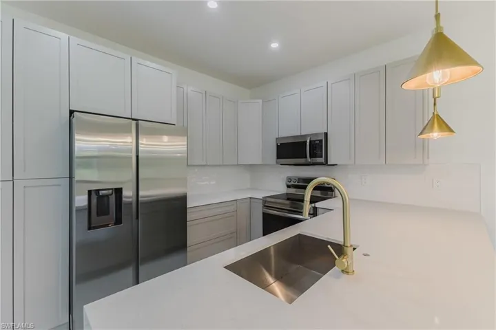Kitchen with appliances with stainless steel finishes, tasteful backsplash, pendant lighting, gray cabinetry, and recessed lighting