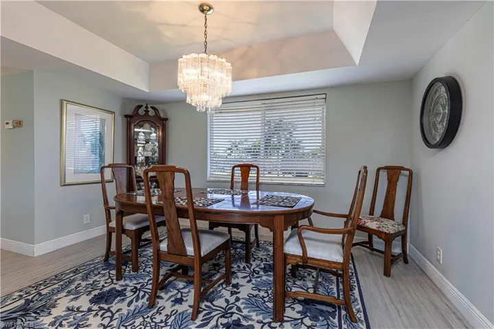 Dining space featuring a chandelier, a tray ceiling, and light wood-style flooring