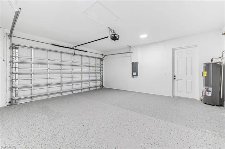 Garage featuring a garage door opener and electric water heater