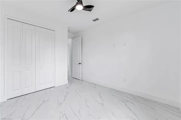 Unfurnished bedroom with a closet, light tile flooring, and ceiling fan