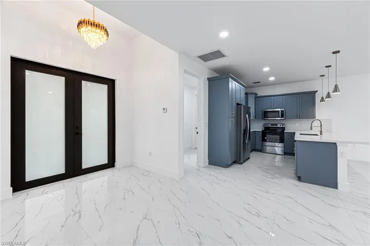 Kitchen featuring light tile flooring, appliances with stainless steel finishes, sink, french doors, and pendant lighting