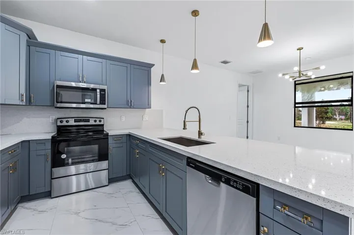 Kitchen with decorative light fixtures, tasteful backsplash, and appliances with stainless steel finishes