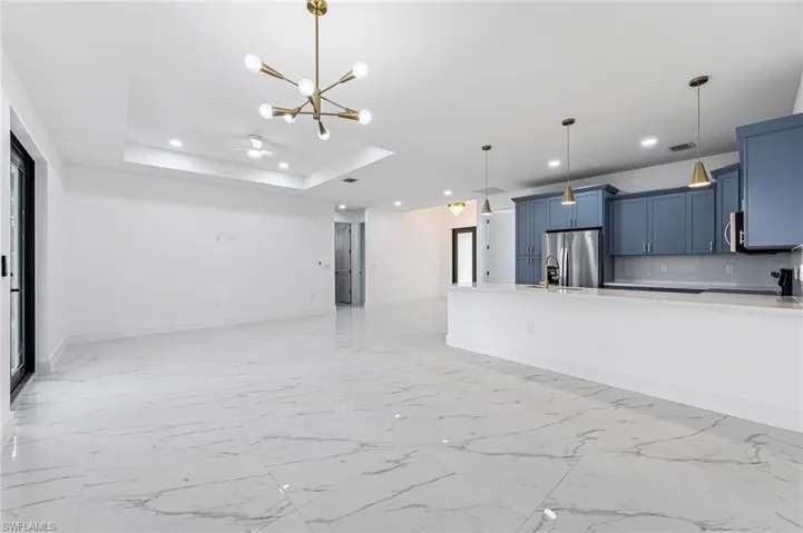 Unfurnished living room with light tile floors, sink, a chandelier, and a raised ceiling