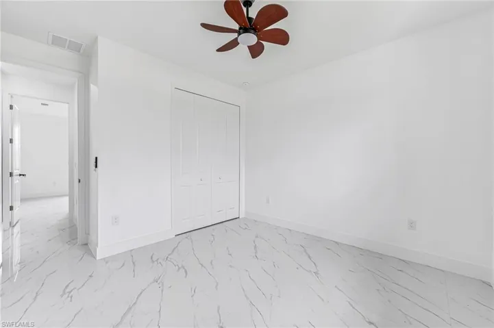 Unfurnished bedroom featuring ceiling fan, a closet, and light tile flooring