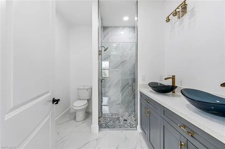 Bathroom featuring tile floors, an enclosed shower, and toilet