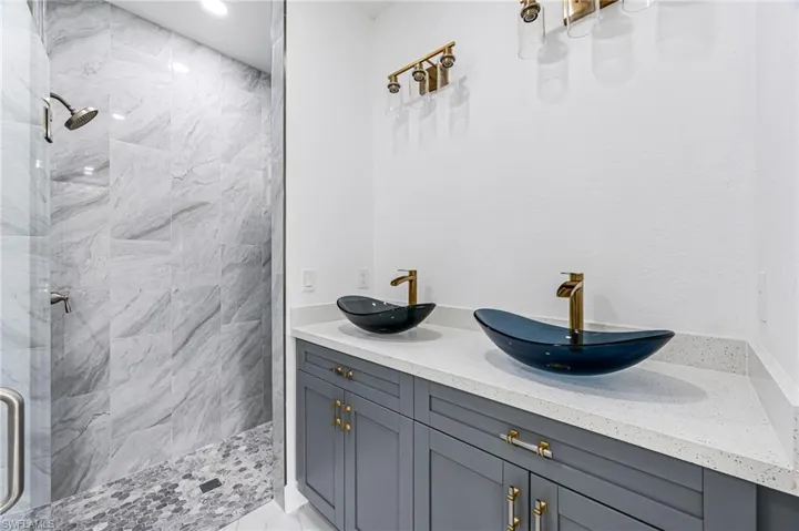 Bathroom with tiled shower and double sink vanity