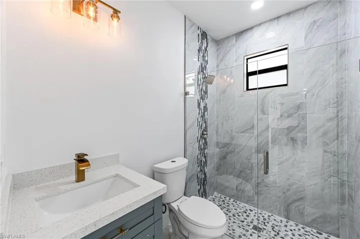 Bathroom with an enclosed shower, vanity, and toilet