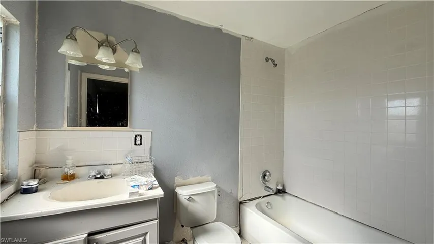 Full bathroom with tasteful backsplash, a textured wall, vanity, and shower / bathtub combination
