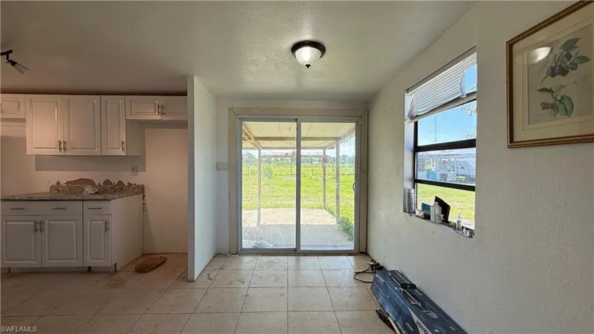 Doorway to outside with a textured ceiling, a textured wall, and light tile patterned flooring
