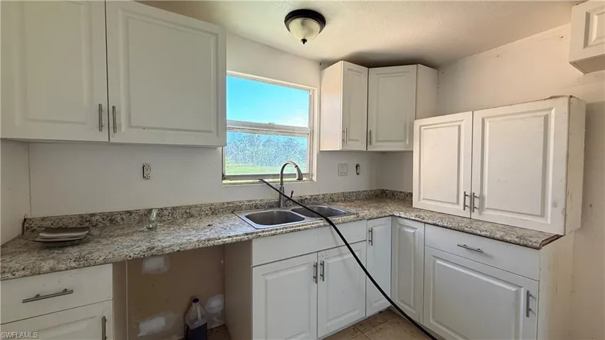 Kitchen featuring white cabinets, light tile patterned floors, and light countertops