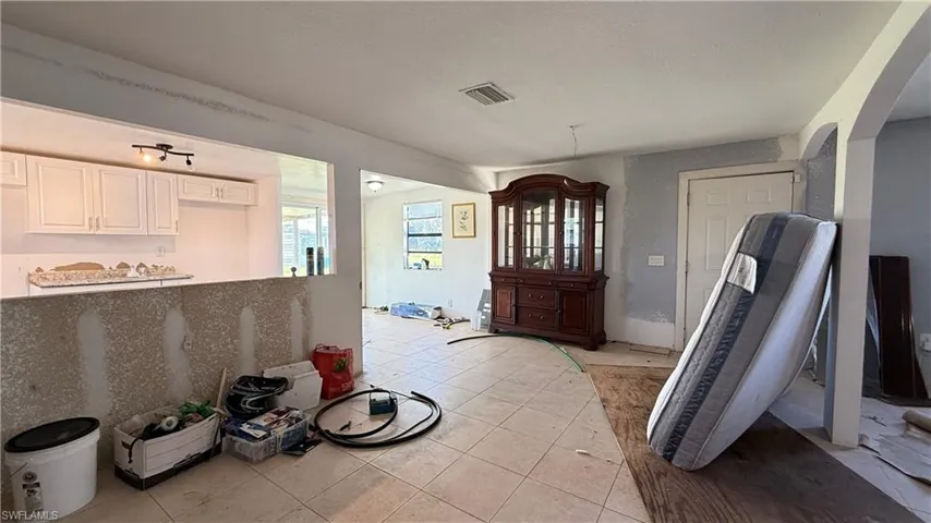 Entryway featuring arched walkways, light tile patterned floors, and a textured ceiling