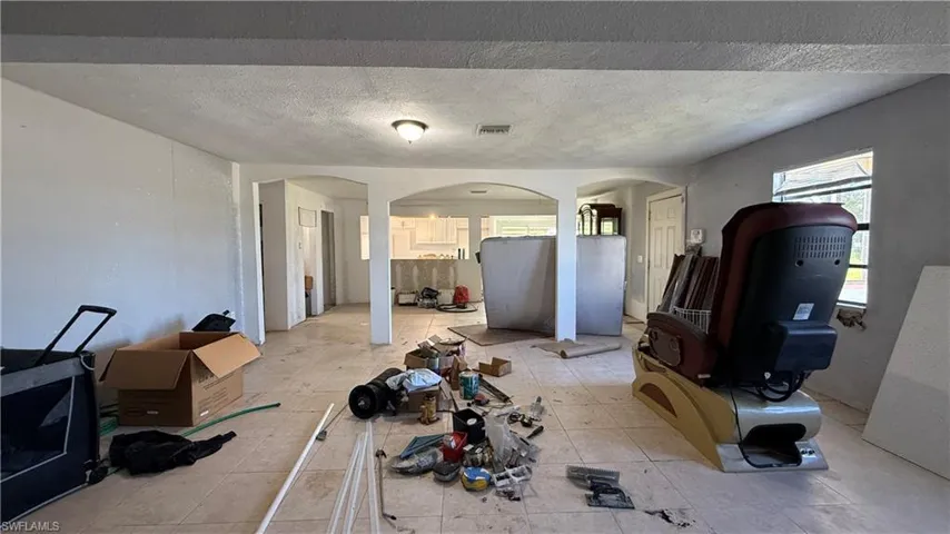 Unfurnished living room with arched walkways and a textured ceiling