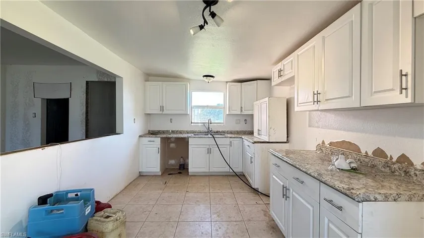 Kitchen featuring white cabinets, a textured ceiling, rail lighting, light countertops, and light tile patterned flooring