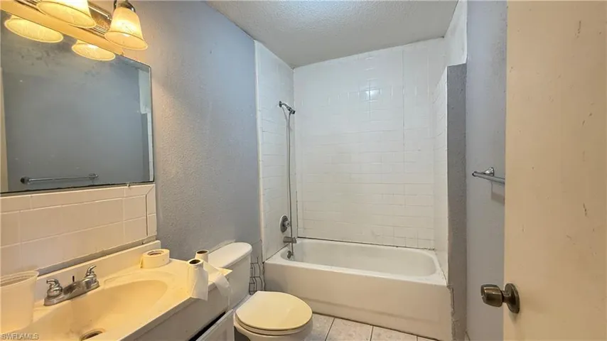 Full bathroom featuring a textured ceiling, vanity, a textured wall, tub / shower combination, and tile patterned floors