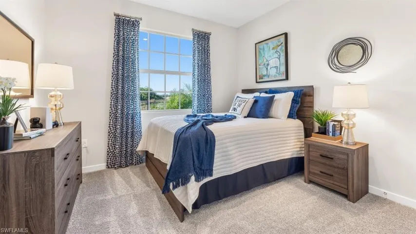 Carpeted room with a multi-pane window, featuring a wood-finish headboard and coordinating dresser and nightstand