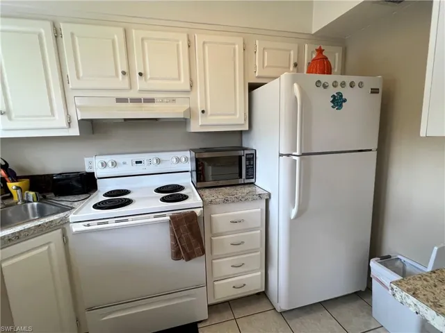Kitchen with sink, white cabinets, white appliances, exhaust hood, and light tile patterned floors