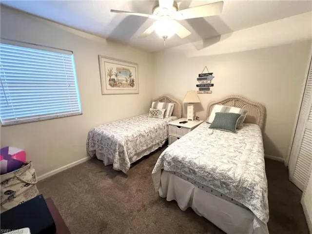 Carpeted bedroom with ceiling fan and a closet