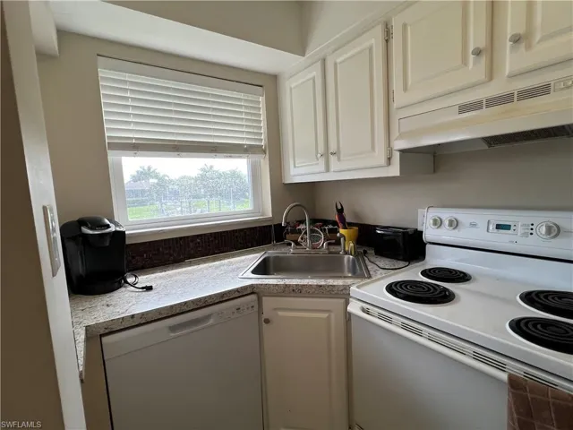 Kitchen with white appliances, white cabinetry, sink, and extractor fan