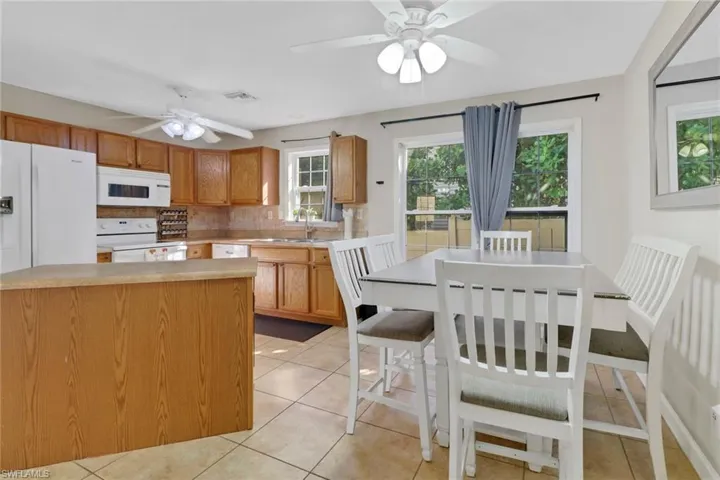 Kitchen featuring a center island, white appliances, sink, decorative backsplash, and light tile patterned floors