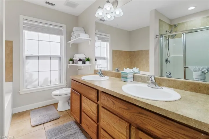 Bathroom with tile patterned flooring, vanity, an enclosed shower, and toilet