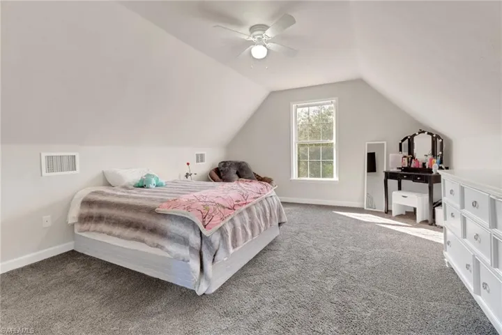 Carpeted bedroom featuring ceiling fan and lofted ceiling