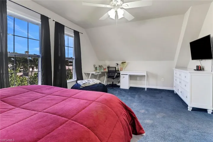 Bedroom featuring dark colored carpet, ceiling fan, and lofted ceiling
