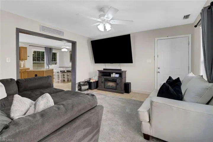Carpeted living room with ceiling fan and a fireplace