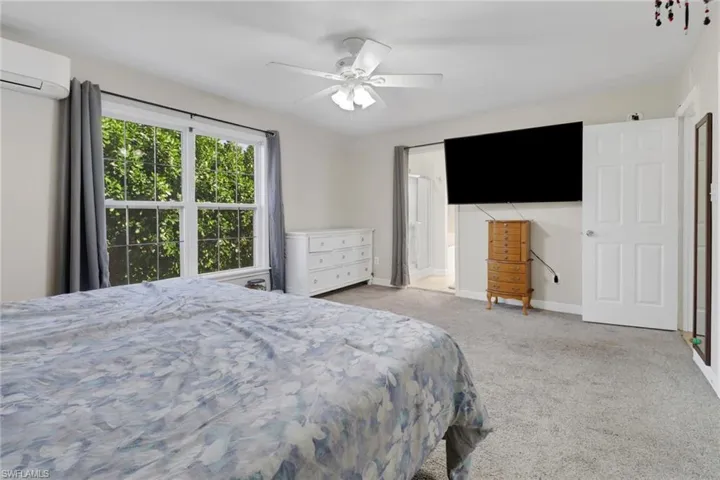 Carpeted bedroom with ceiling fan and an AC wall unit
