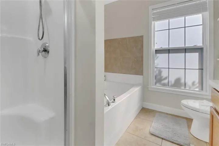 Bathroom featuring tile patterned flooring, vanity, toilet, and a tub