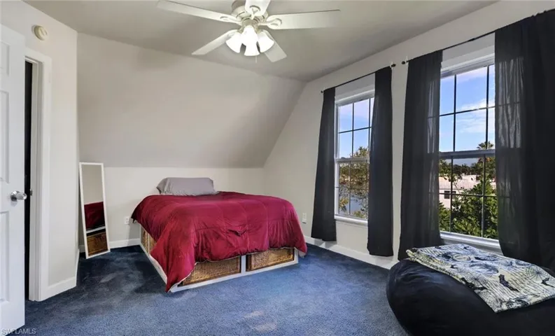 Carpeted bedroom with ceiling fan and vaulted ceiling