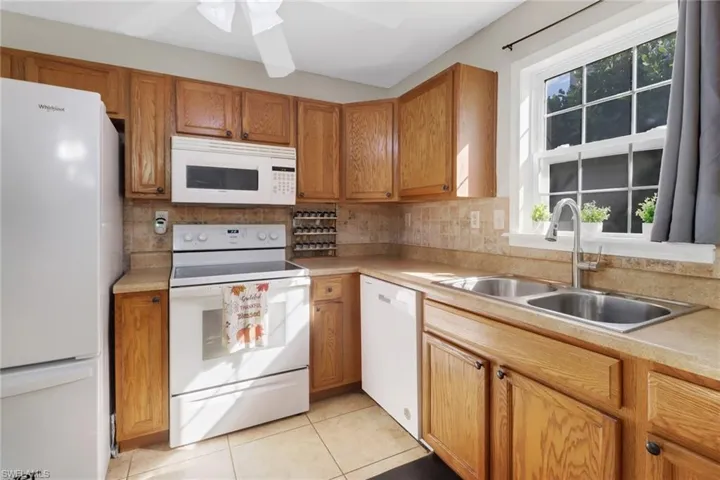 Kitchen with white appliances, backsplash, a wealth of natural light, and sink